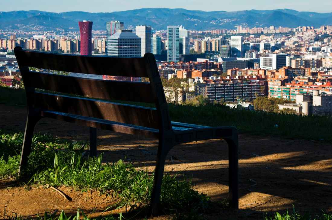 brown wooden bench with metal frame surrounded by building scenery